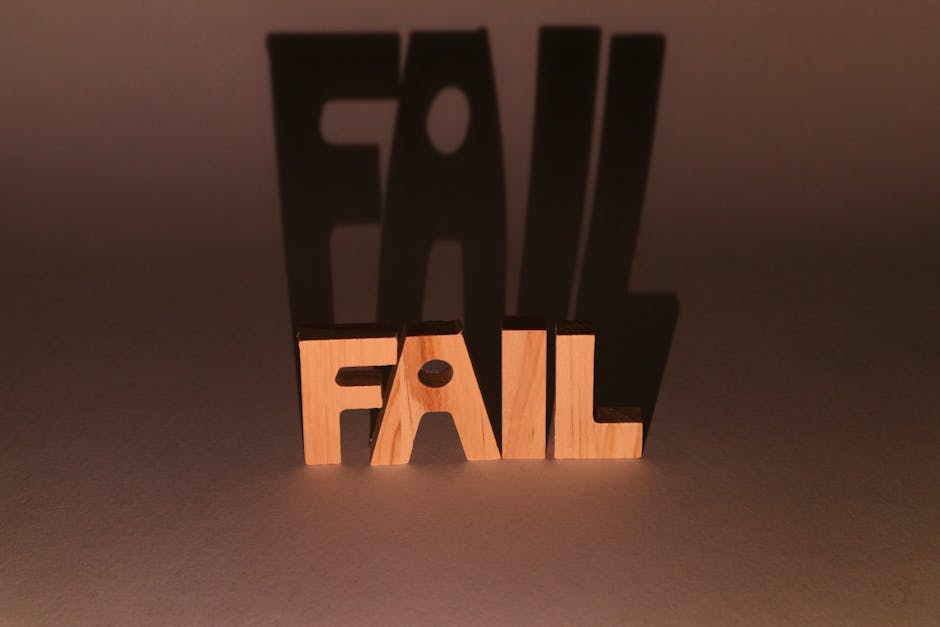 Wooden blocks spelling 'FAIL' casting a dramatic shadow against a brown background in a studio setup.