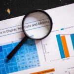 Close-up of business charts with magnifying glass highlighting data insights.