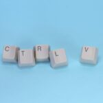Close-up of CTRL V keyboard keys on a blue background. Minimalist tech concept.