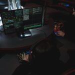 A group of people in a dark room working on computers, related to cybersecurity.