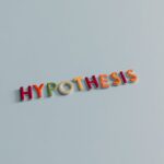 Multicolored letters spell 'HYPOTHESIS' on a light blue surface, conveying research and creativity.