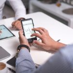 Business professionals collaborating with smartphones and tablets analyzing digital charts.