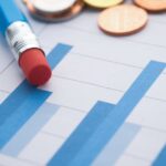 Close-up of bar graphs with a pencil and coins, symbolizing financial analysis.