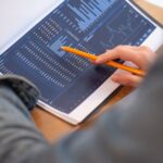 Focused image of hands analyzing business graphs and charts in a folder, highlighting data insights.