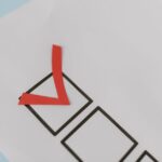Close-up of a red check mark on a crisp white paper with black boxes, symbolizing completion.