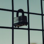 Close-up of a steel padlock on a mesh fence, symbolizing protection and security.